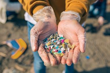 Someone holding small pieces of plastic on a beach